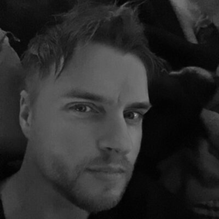 A close-up black-and-white portrait of a young man with tousled hair.